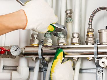 Storage Water Heaters — Worker Hands Fixing Heating System in Tulare, CA Storage Water Heaters — Worker Hands Fixing Heating System in Tulare, CA