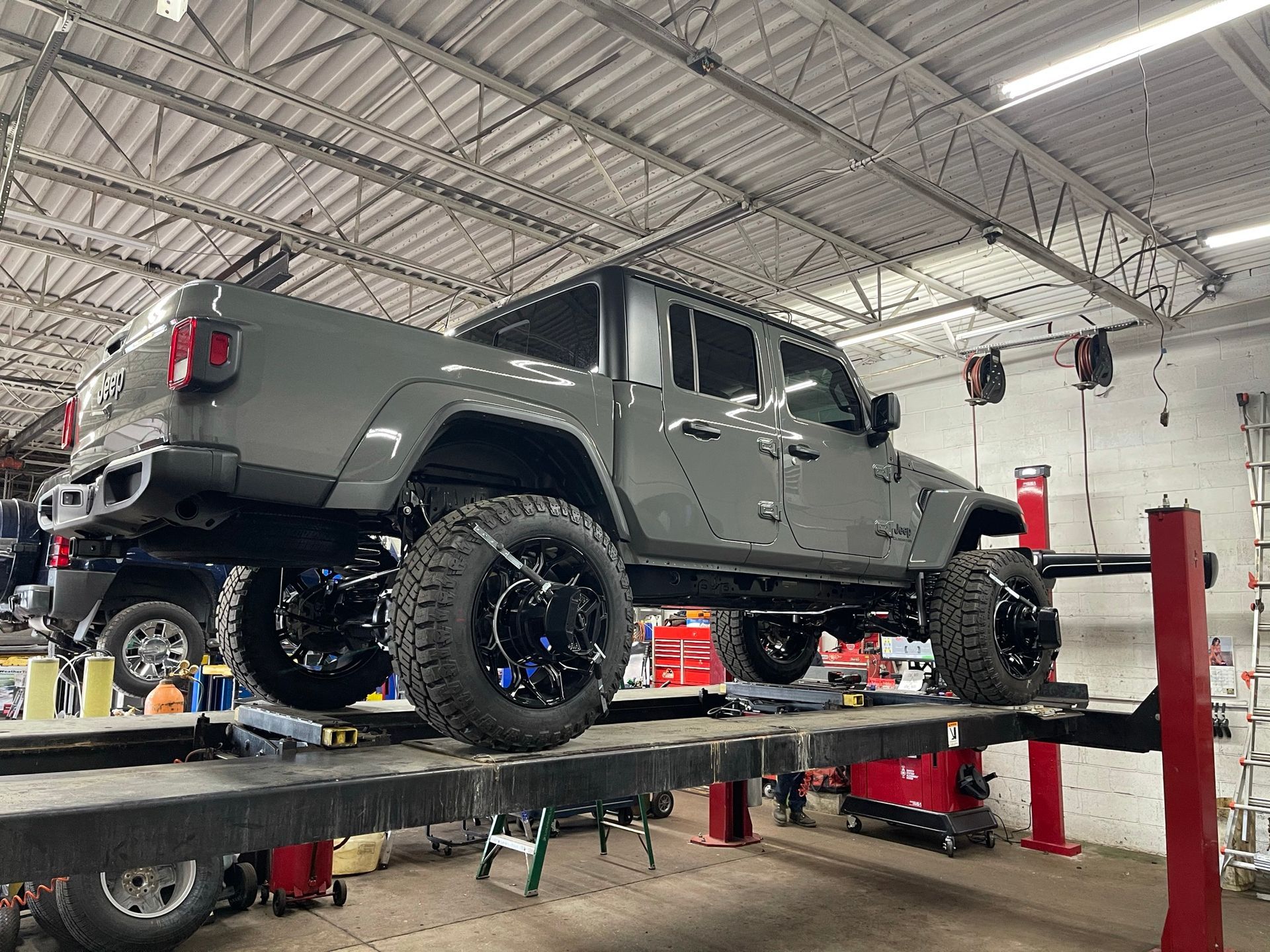 A jeep is sitting on a lift in a garage.