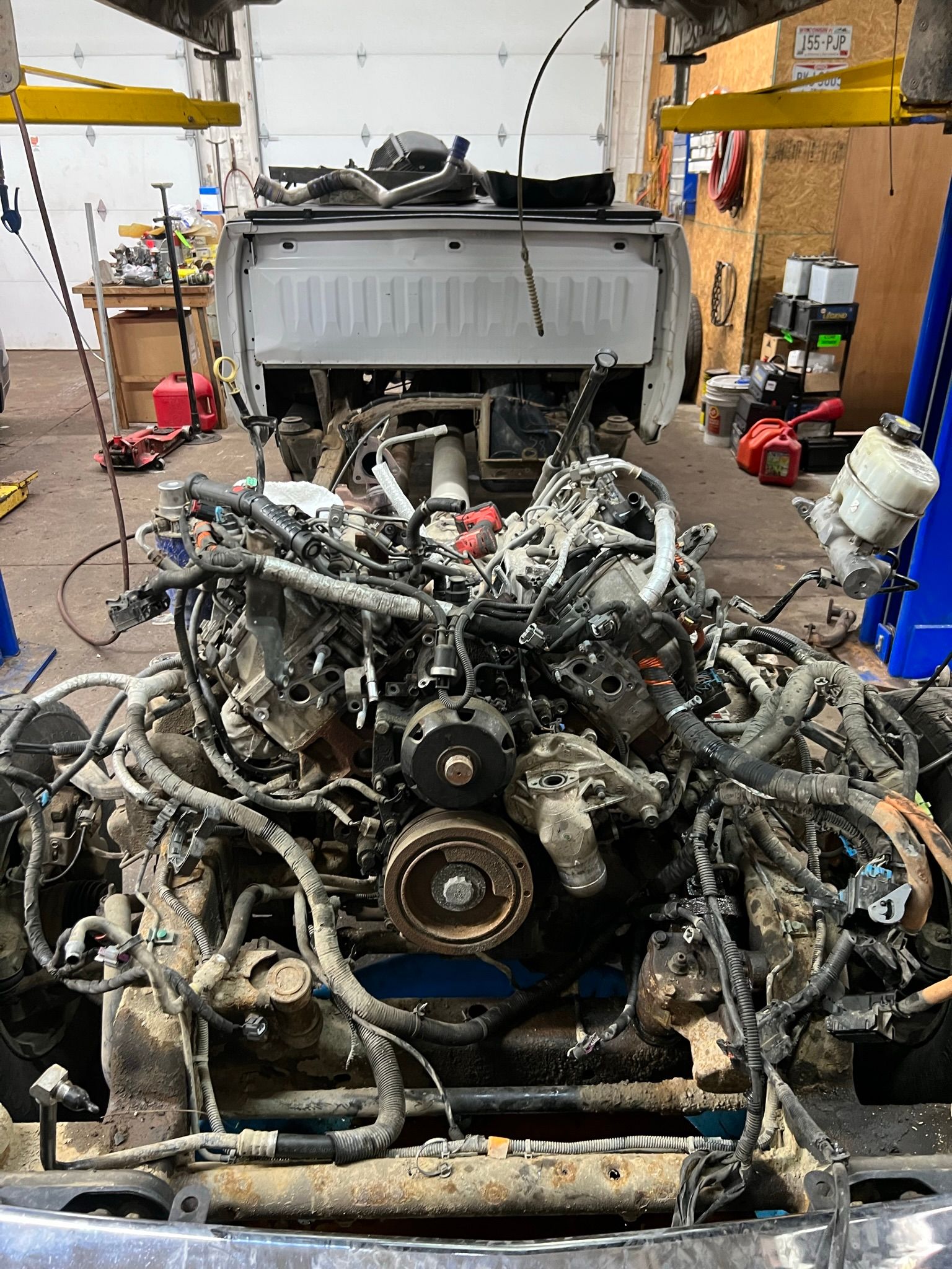 The engine of a truck is being dismantled in a garage.