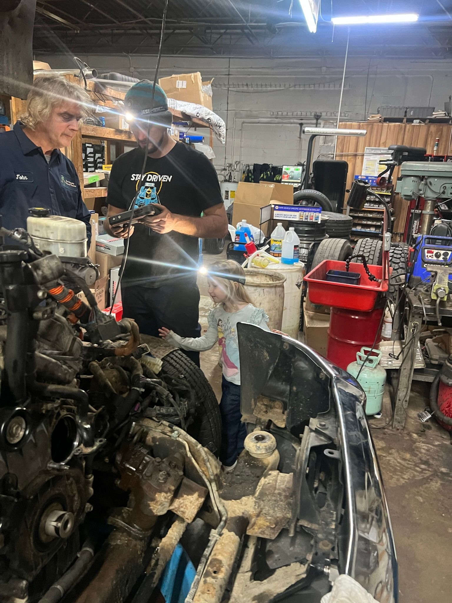 A group of men are working on a car engine in a garage.
