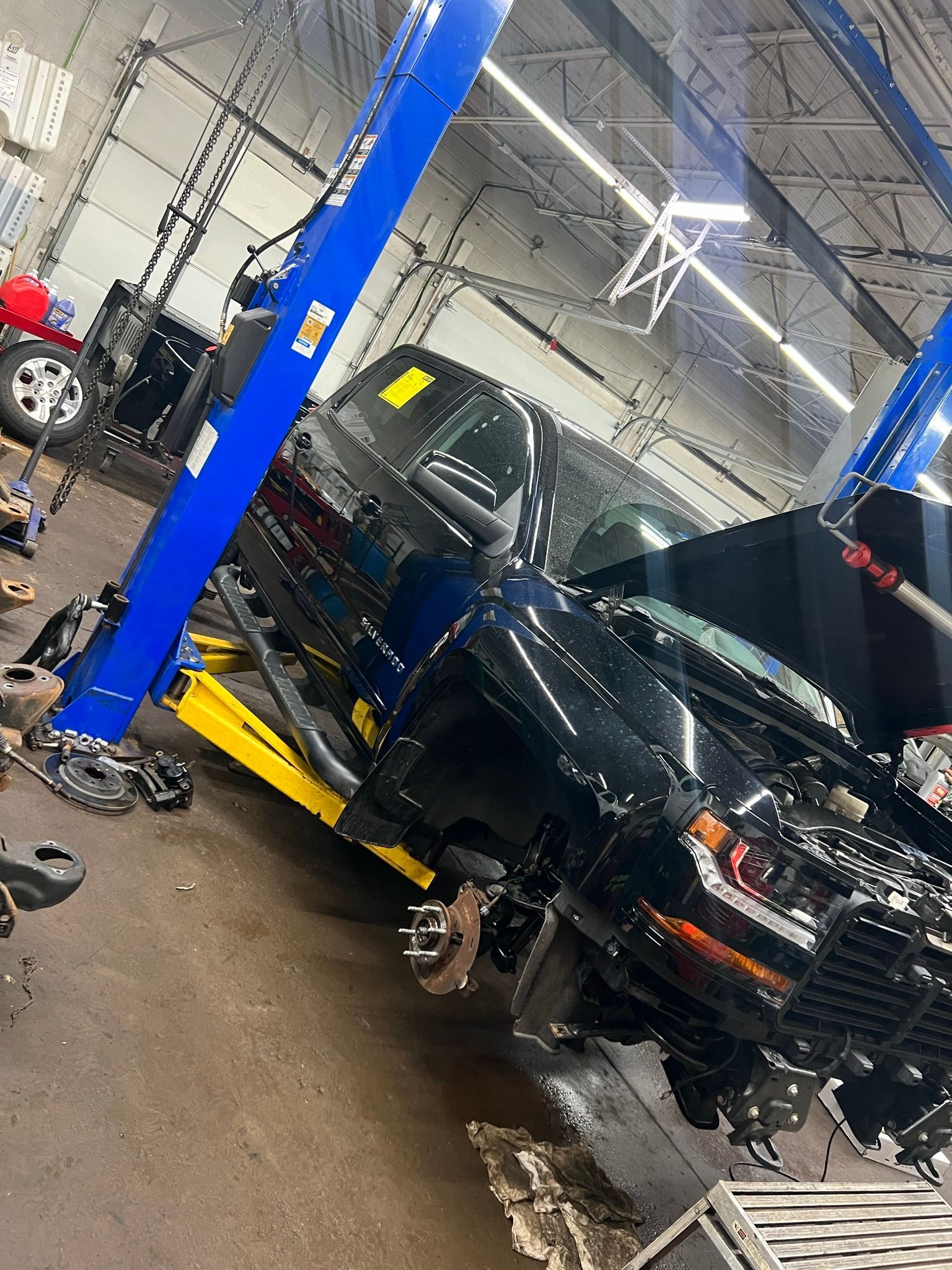 A black truck is sitting on a lift in a garage.