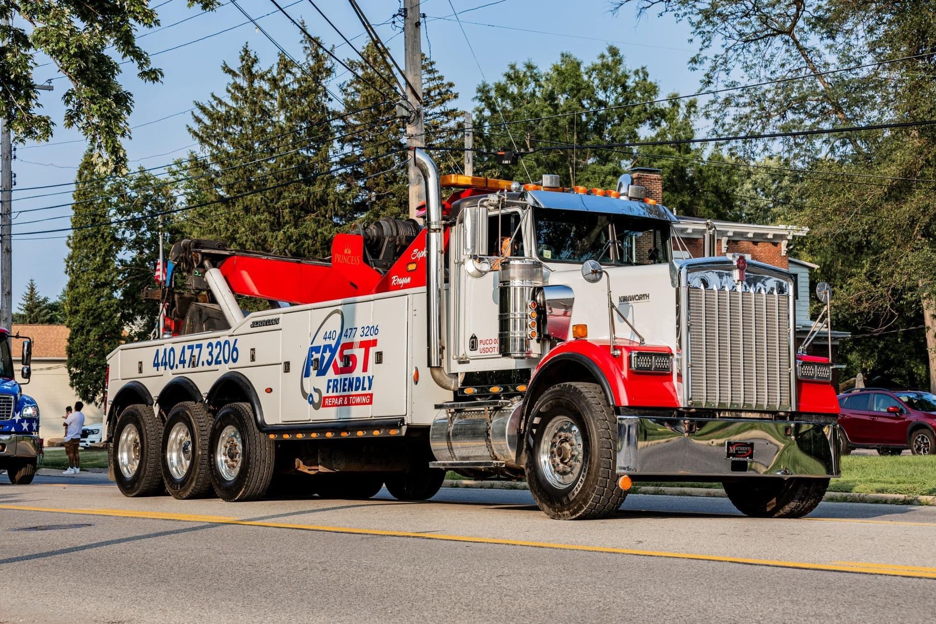 A red and white tow truck is parked on the side of the road.