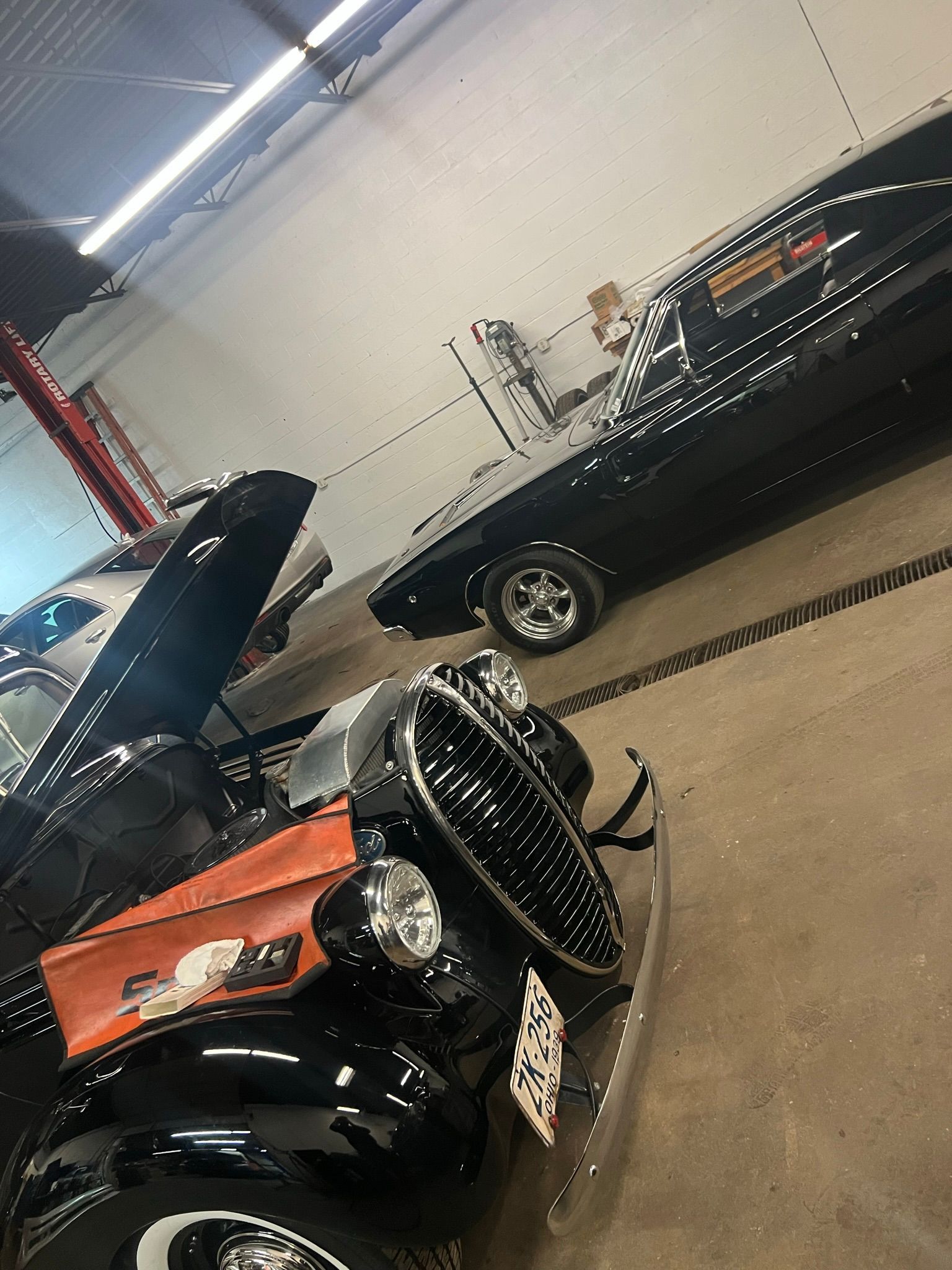 A black car is parked next to an orange car in a garage.