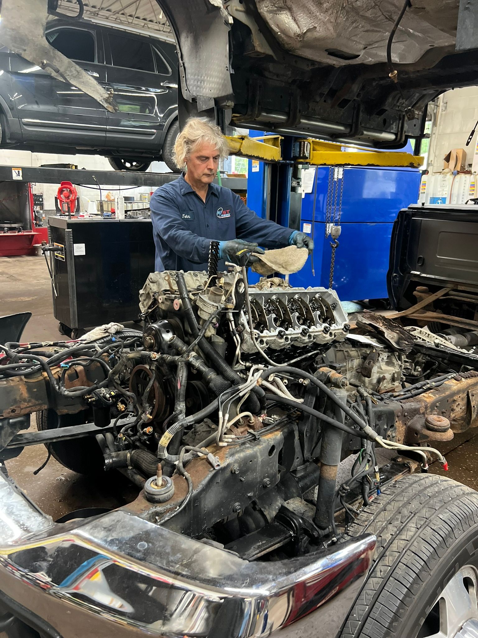 A man is working on the engine of a truck in a garage.