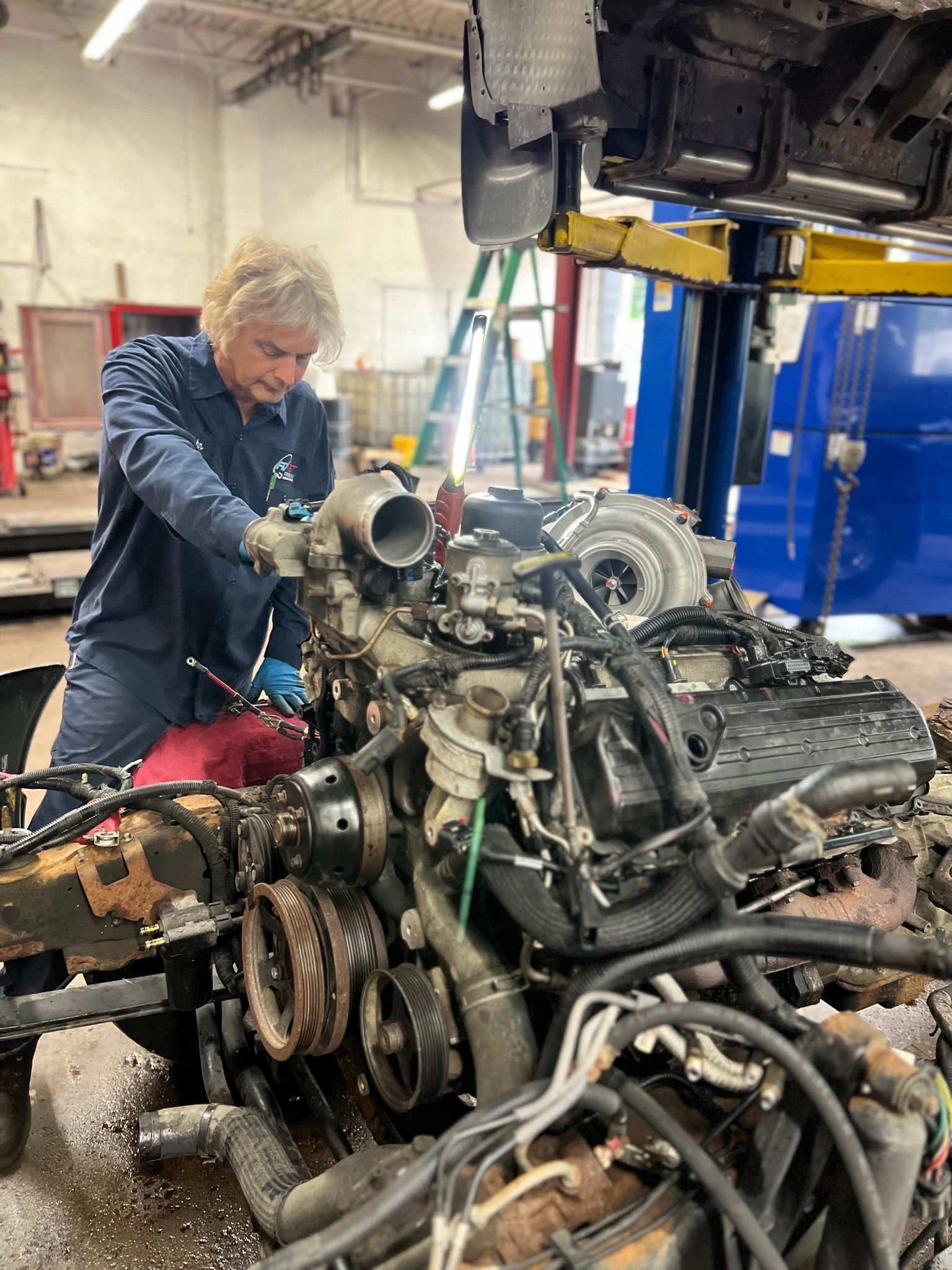 A man is working on a large engine in a garage.