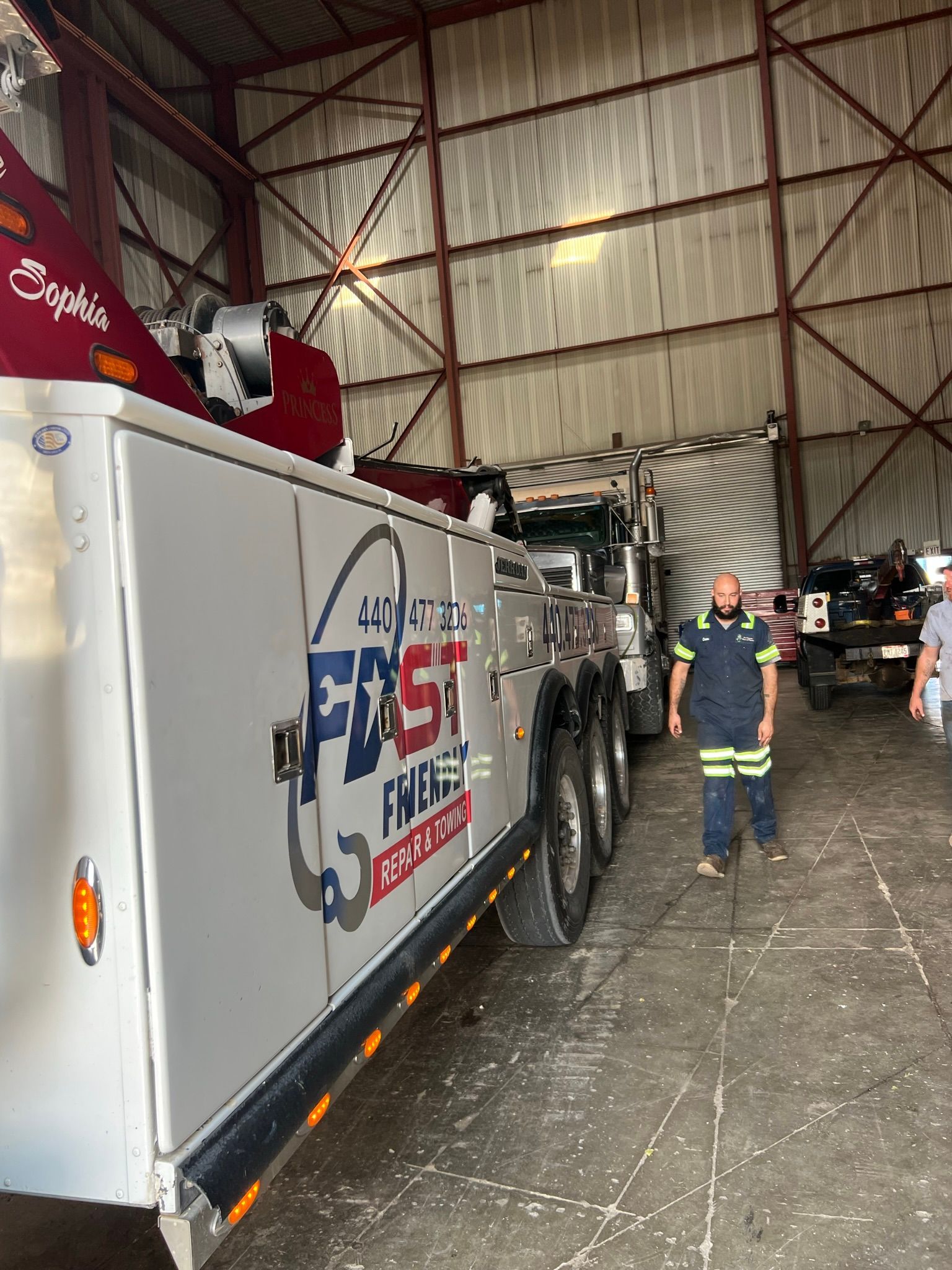 A man is standing next to a tow truck in a garage.