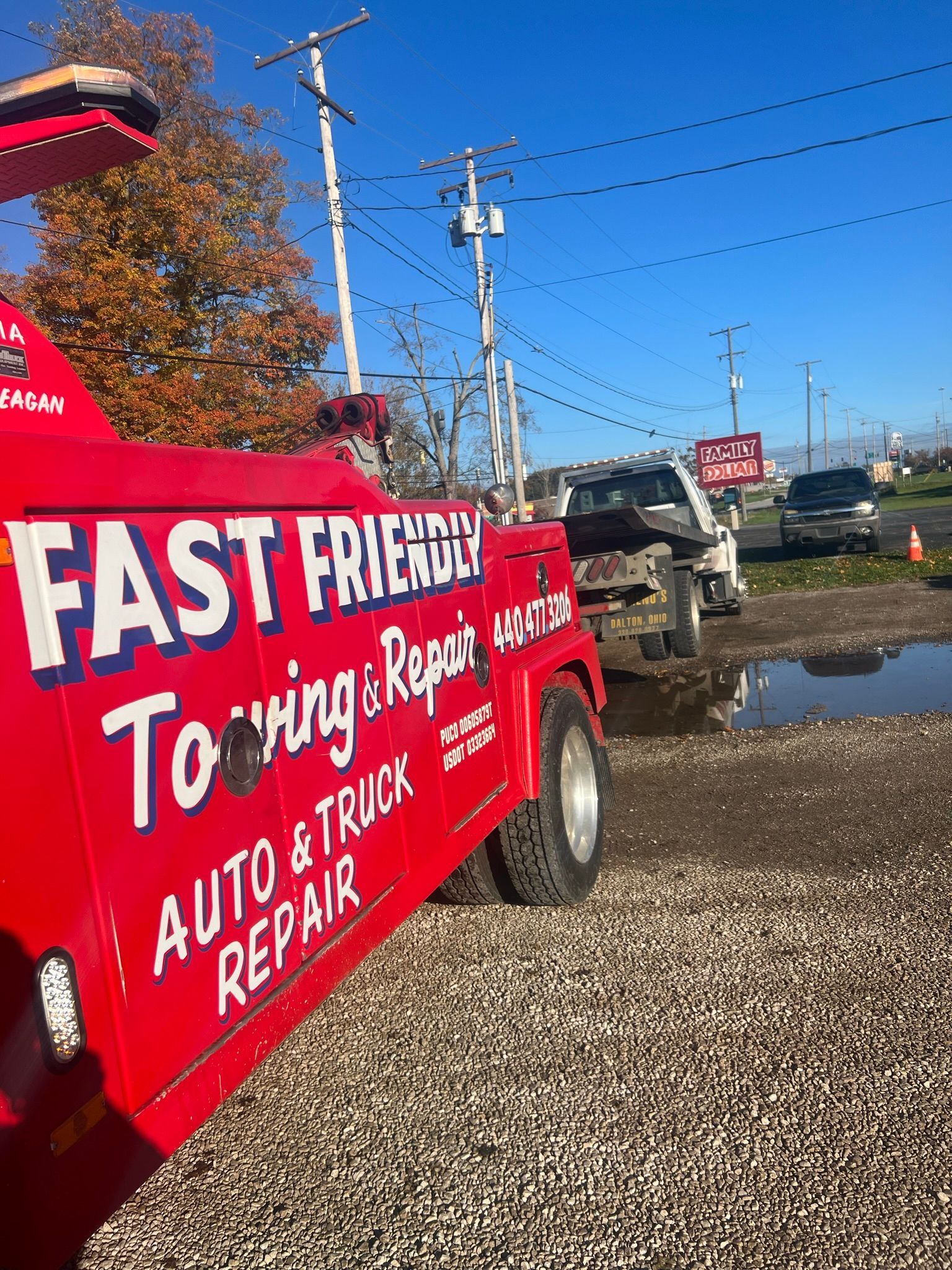 A red tow truck is parked in a gravel lot.