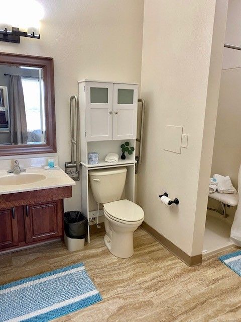 A bathroom with a toilet , sink and mirror.