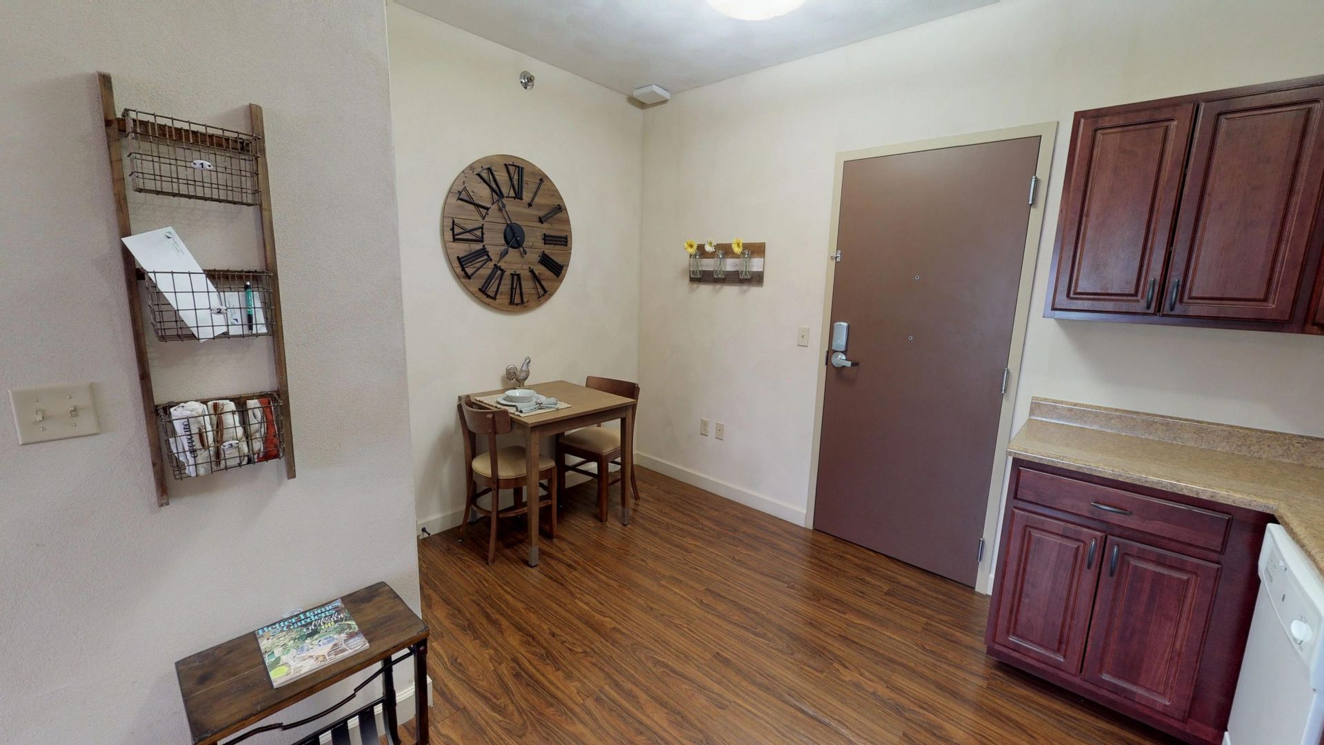 A living room with a table and chairs and a clock on the wall.