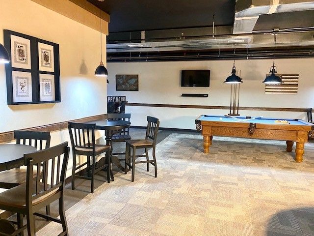 A pool table is in a room with tables and chairs.