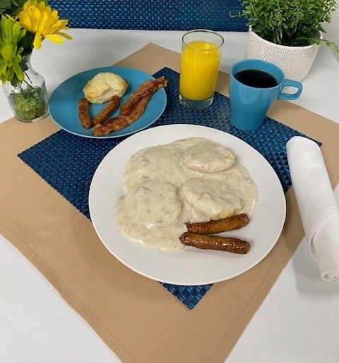 A plate of food on a table with a cup of coffee and a glass of orange juice