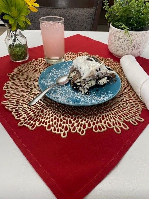 A slice of cake on a plate with a spoon on a place mat