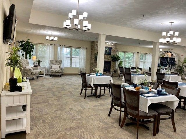 A large dining room with tables and chairs in a nursing home.