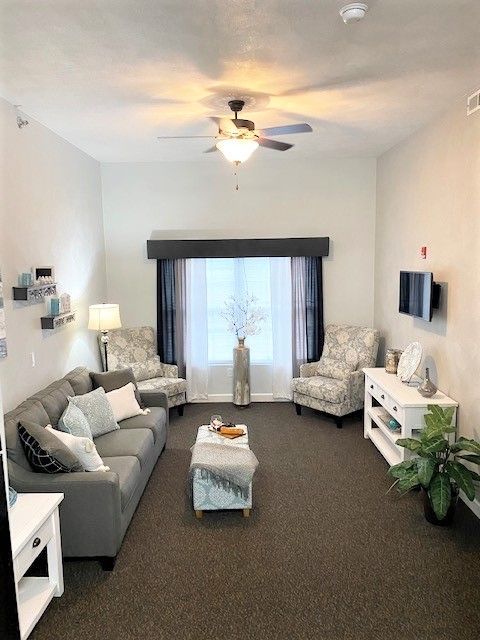 A living room with a couch , chairs , and a television.