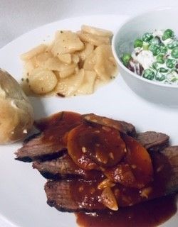 A white plate topped with meat potatoes and a bowl of peas