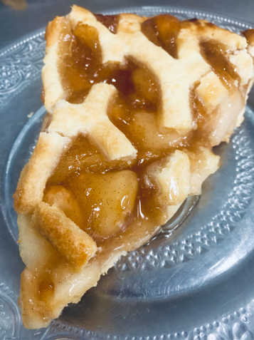 A slice of apple pie on a glass plate