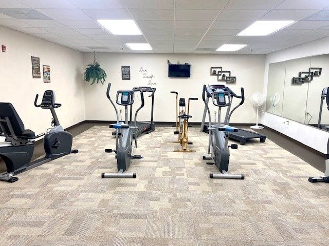 A gym with a lot of exercise equipment and a large mirror