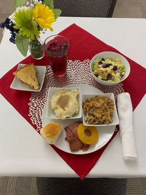 A plate of food on a table with a vase of flowers in the background