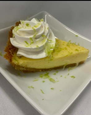 A slice of key lime pie with whipped cream on a white plate.