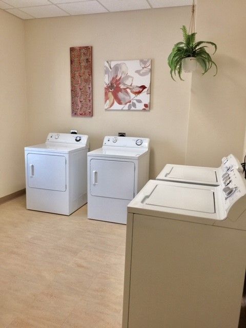 A laundry room with two washers and two dryers