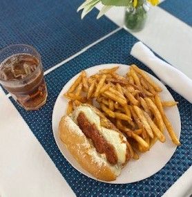 A hot dog and french fries are on a plate on a table.