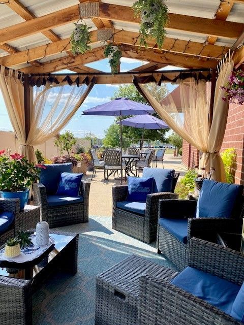 A patio with chairs and umbrellas under a canopy