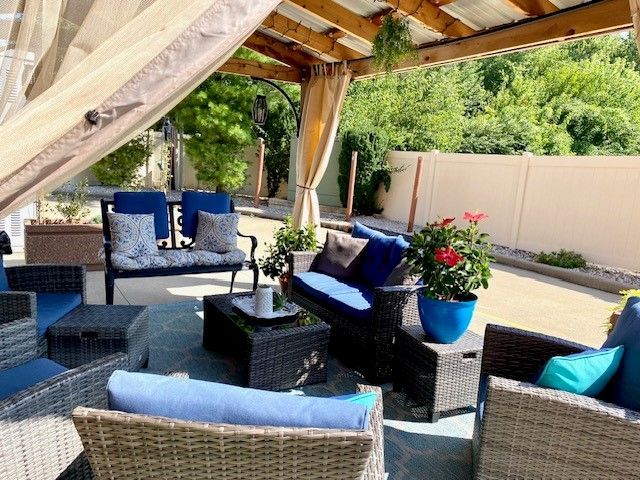 A patio with wicker furniture and a couch under a canopy.