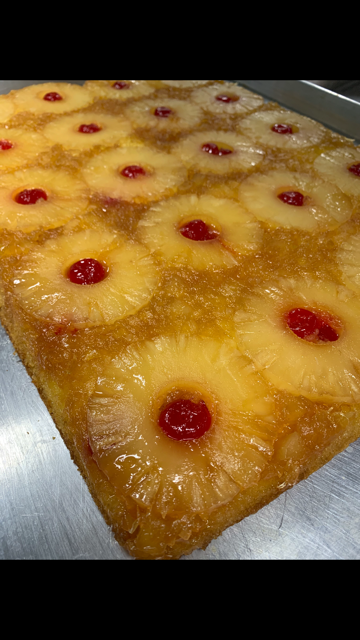 A pineapple upside down cake with cherries on top.