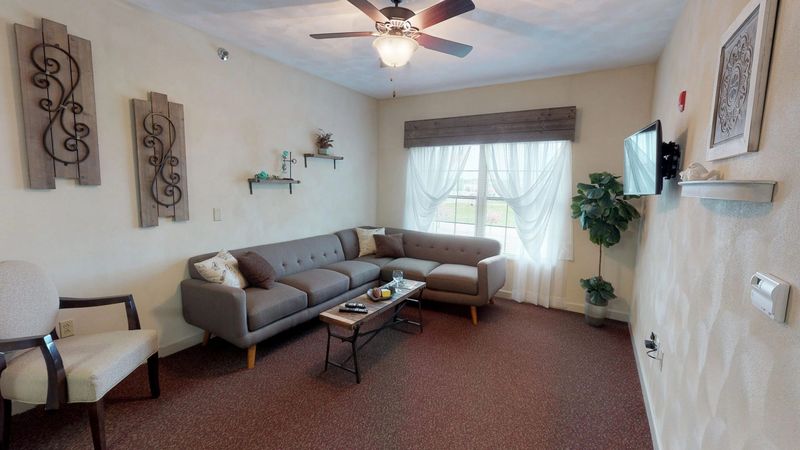 A living room with a couch , chairs , coffee table and ceiling fan.