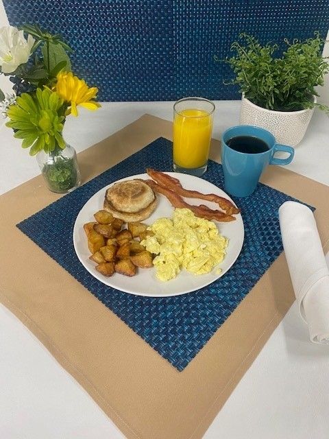 A plate of food with eggs bacon and potatoes on a table