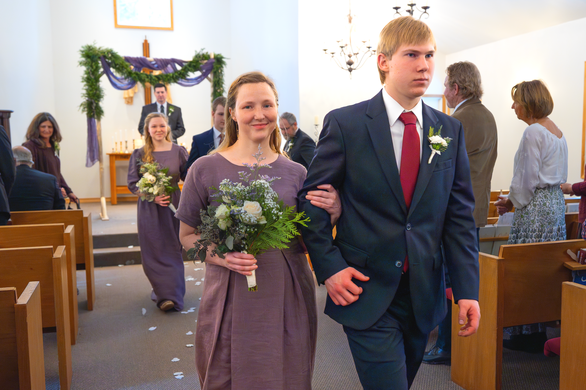 Bridesmaid and groomsmen walking down church aisle