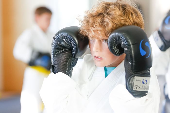 Focused boy punching with boxing gloves