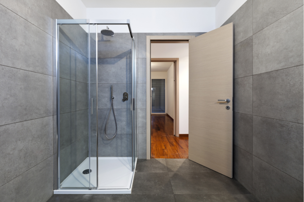 A bathroom with a walk in shower and a door open