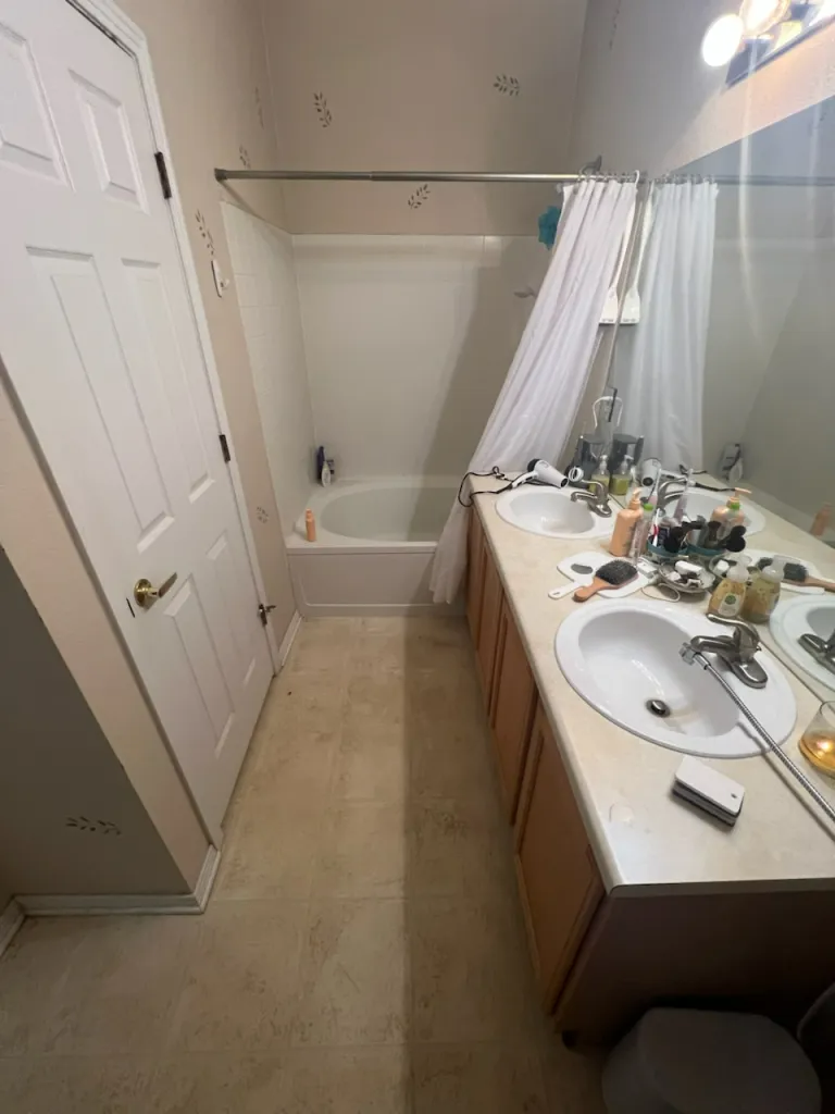 A bathroom with two sinks , a tub , and a mirror.