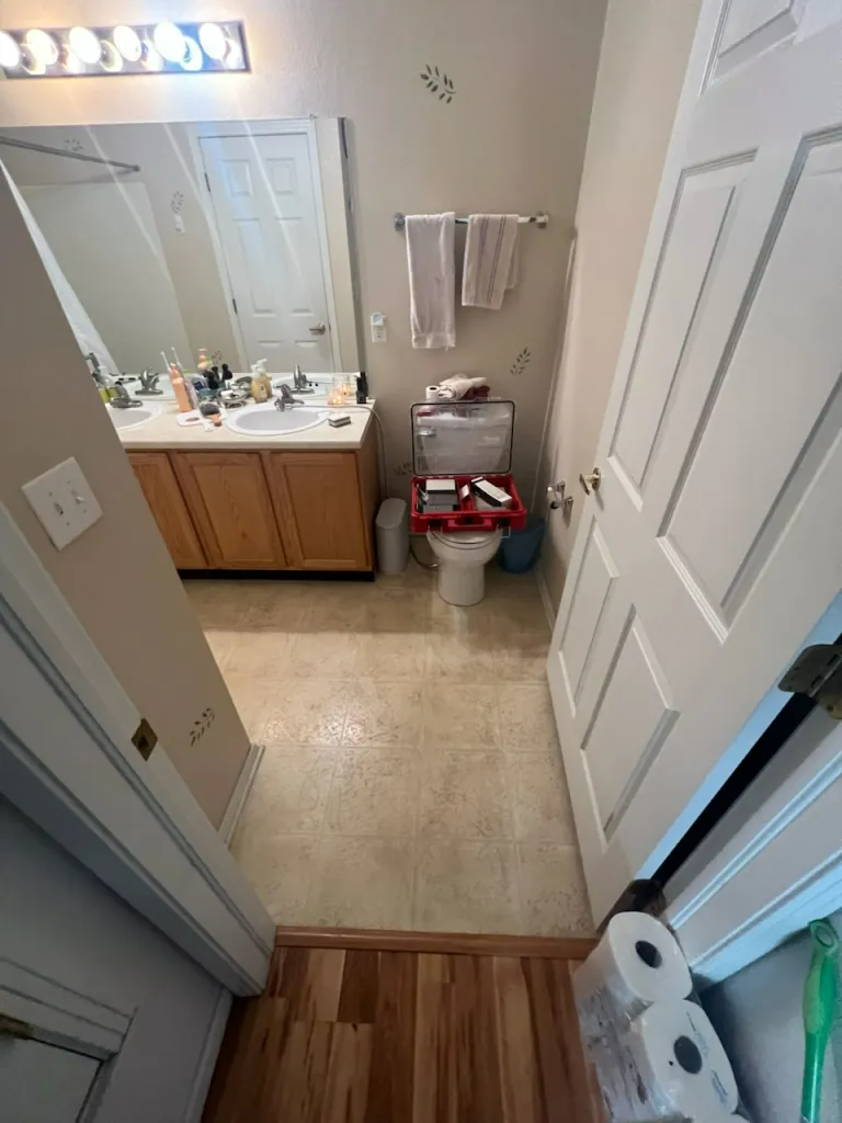 A bathroom with a toilet , sink and mirror.