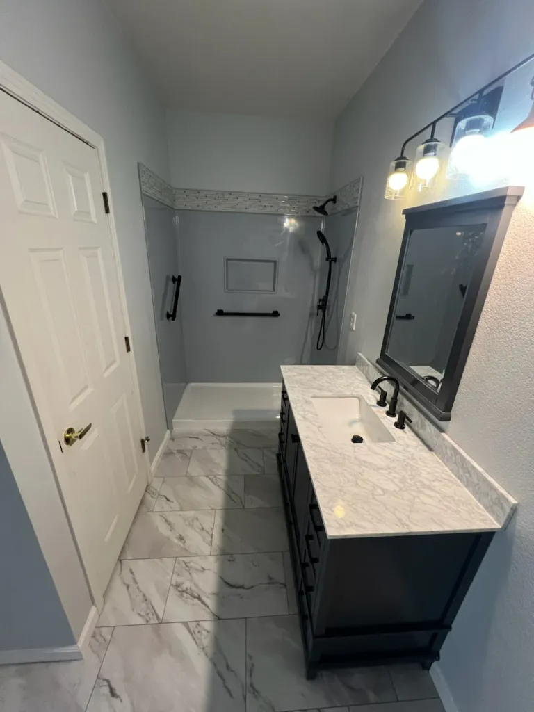 A bathroom with a sink , mirror and shower.
