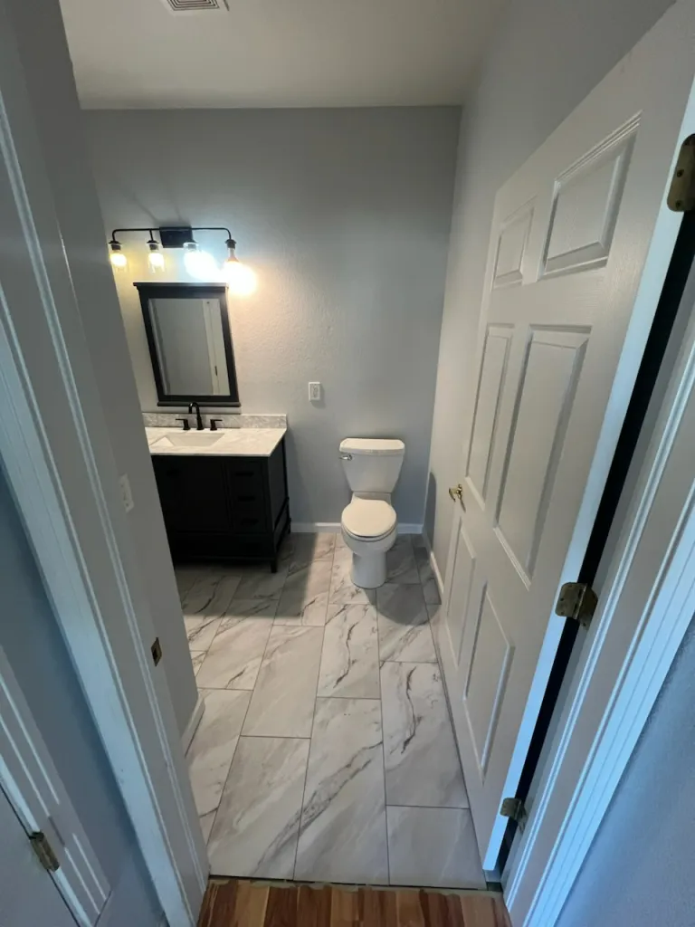 A bathroom with a toilet , sink and mirror.