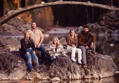 A group of people are sitting on rocks next to a river.