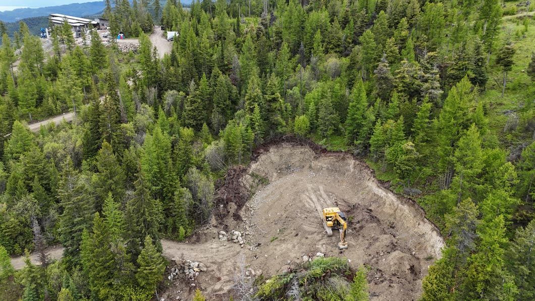An aerial view of a bulldozer digging in the middle of a forest.