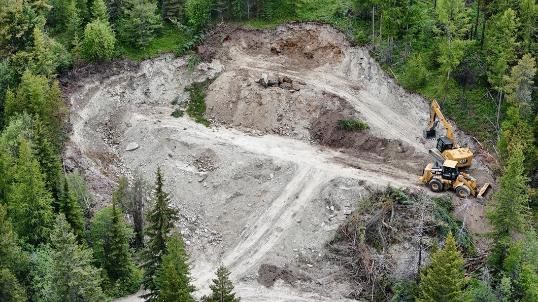 An aerial view of a construction site in the middle of a forest.