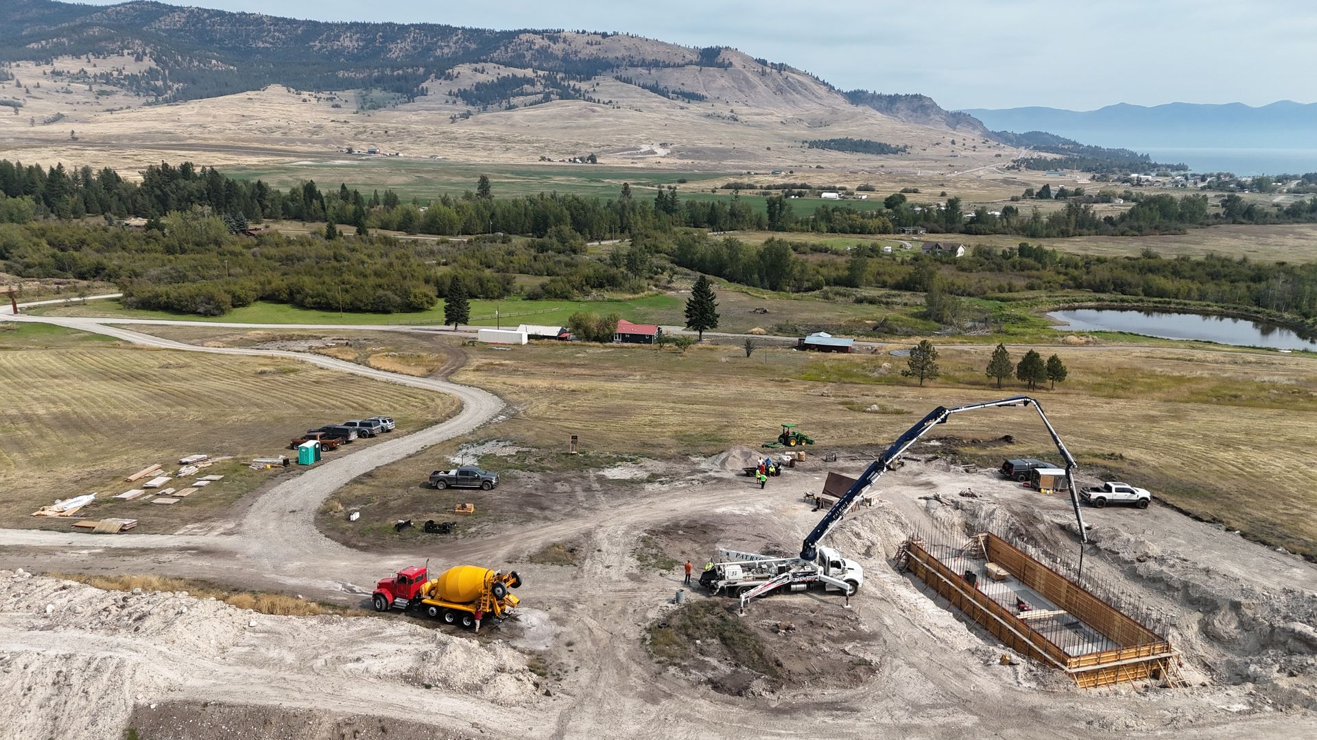 Yellow Caterpillar wheel loader and excavator working on a construction site. Overcast sky, dirt ground.