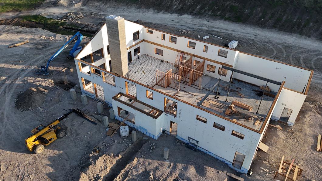 An aerial view of a house under construction in the middle of a dirt field.