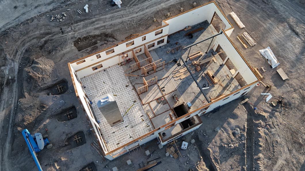 An aerial view of a building under construction in the middle of a dirt field.
