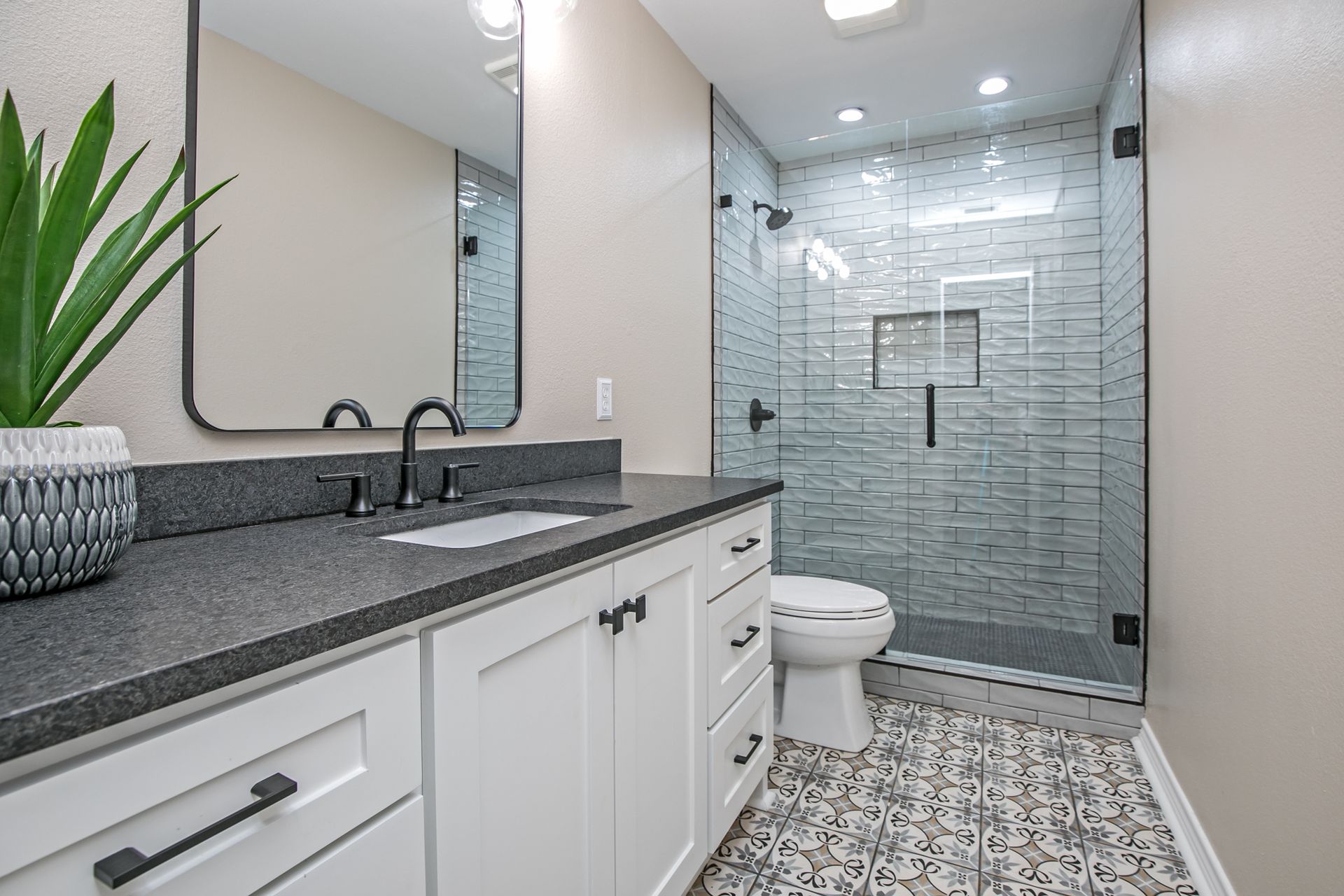 A bathroom with a toilet , sink , mirror and walk in shower.