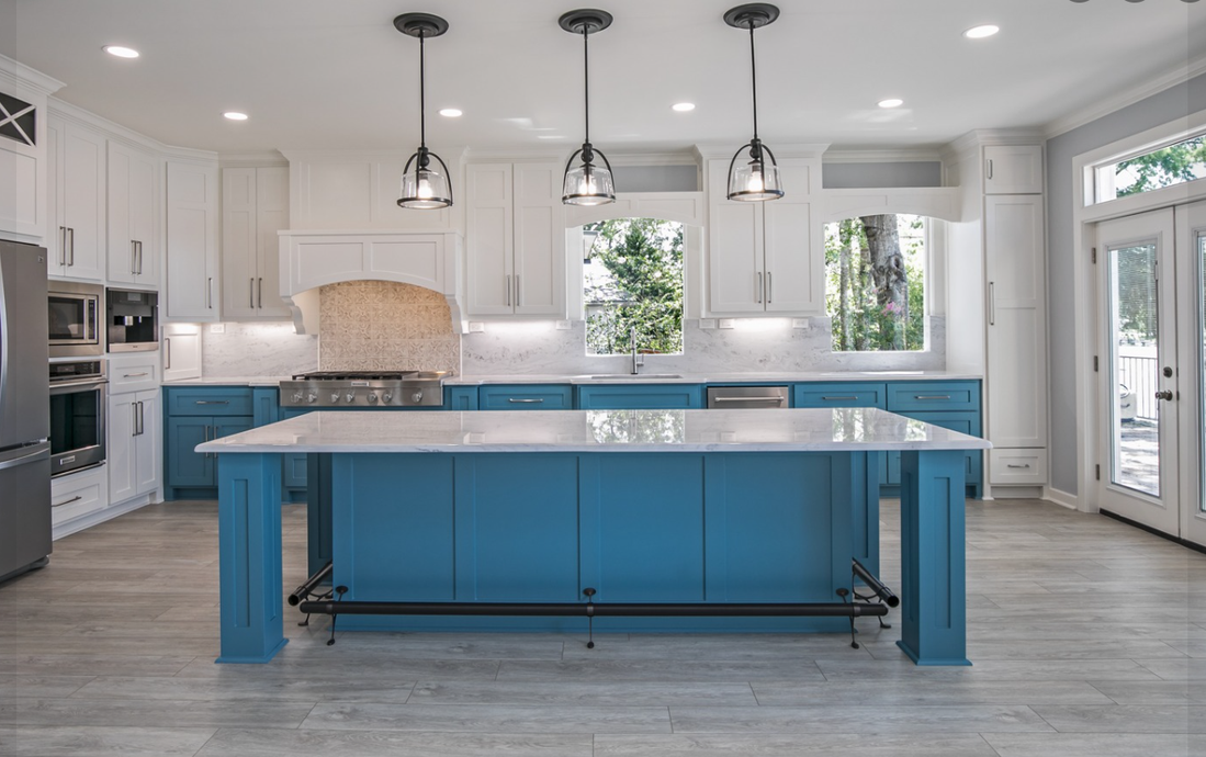 A kitchen with blue cabinets and a large island in the middle.