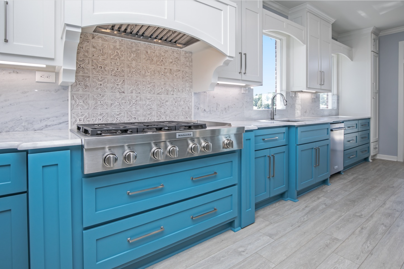 A kitchen with blue cabinets and a stove top oven.