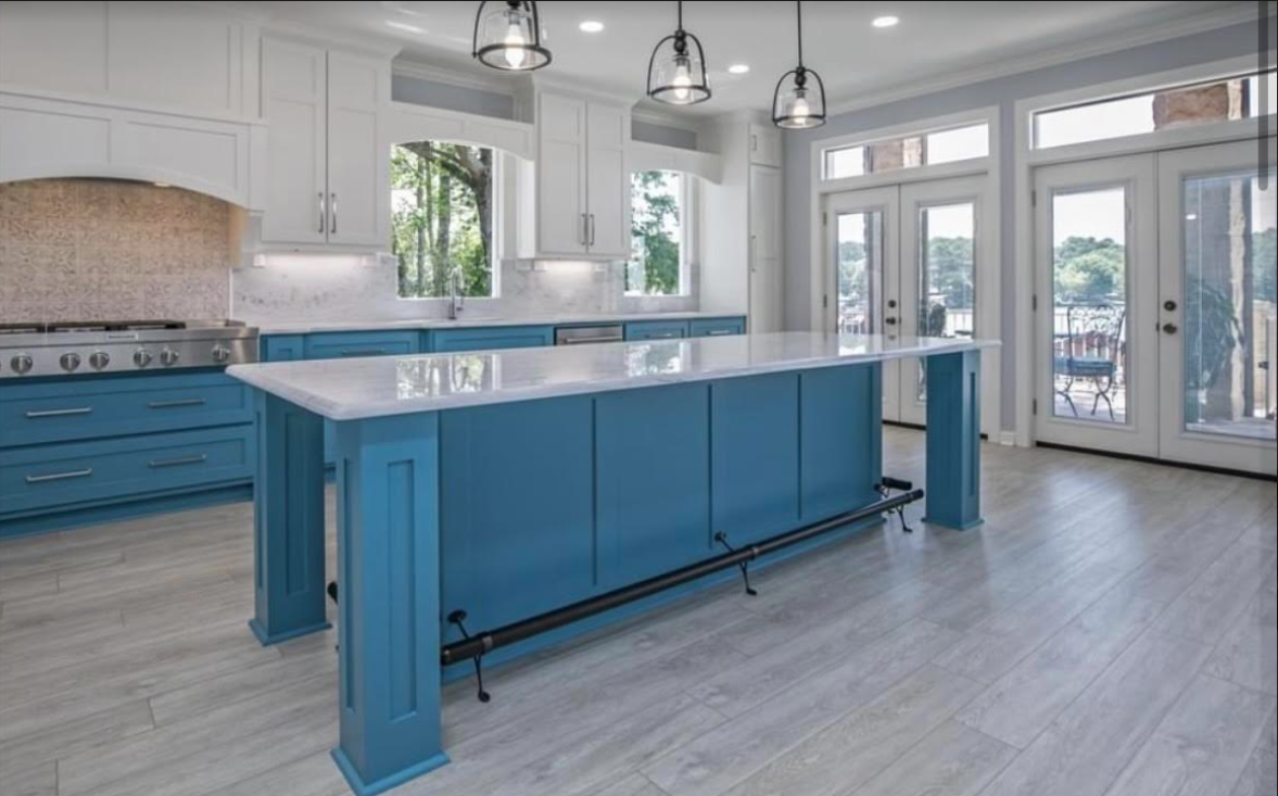 A kitchen with blue cabinets and a large island in the middle.