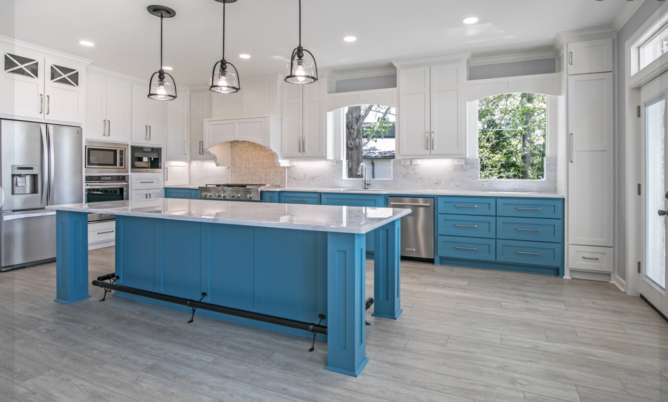 A kitchen with blue cabinets , white cabinets , stainless steel appliances , and a large blue island.