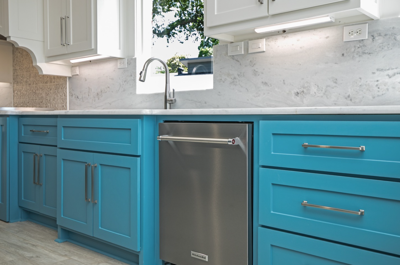 A kitchen with blue cabinets and a stainless steel dishwasher.