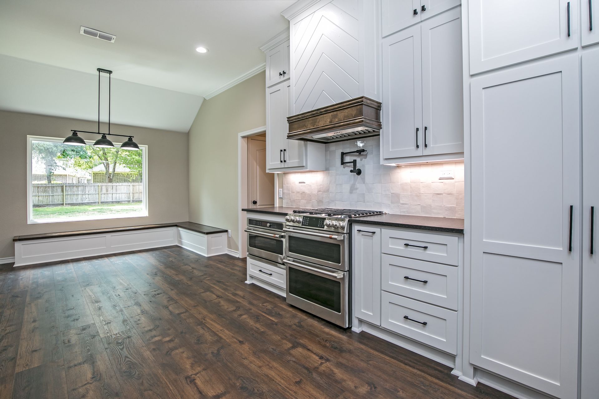A kitchen with white cabinets , stainless steel appliances , and hardwood floors.